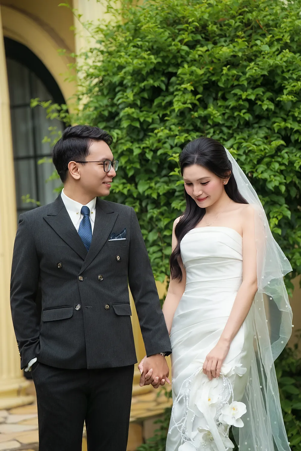 Chú rể và cô dâu nắm tay nhau trước khu vườn